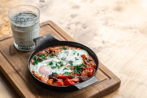 Shakshuka in una padella e un bicchiere di ayran cibo sano e gustoso