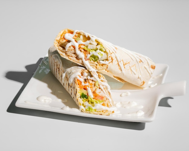 Shawarma classico con pollo, salsa e verdure su piatto bianco primo piano isolato