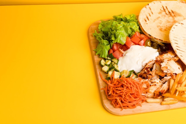 Shawarma con pollo su una tavola di legno vista laterale sfondo giallo