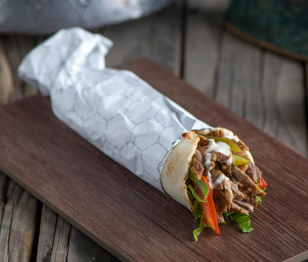 Shawarma di pollo libanese servito in una vista laterale del piatto su uno sfondo di tavolo in legno