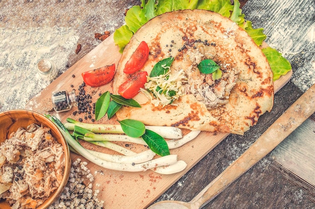 Shawarma in pane pita sottile con pollo e verdure su un tavolo di legno