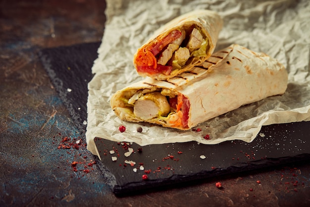 Shawarma tradizionale orientale con pollo e verdure, Doner Kebab con salse su ardesia. Fast food. Cibo orientale.