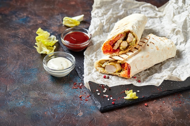 Shawarma tradizionale orientale con pollo e verdure, Doner Kebab con salse su ardesia. Fast food. Cibo orientale.