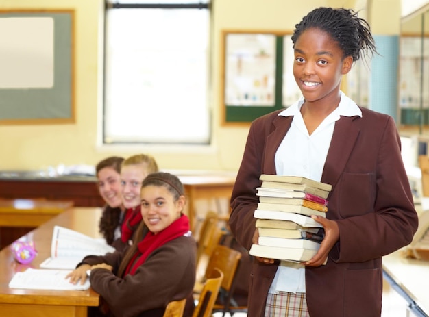 Shes an Astudent Sorridente giovane studente di scuola superiore in possesso di libri mentre si trova in classe