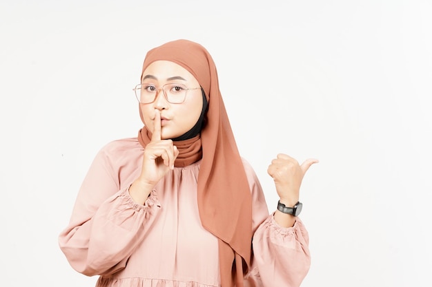 Shh gesto che presenta e indica il prodotto laterale utilizzando il pollice della bella donna asiatica che indossa l'hijab