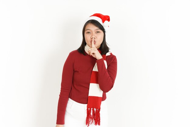 Shh taci di bella donna asiatica che indossa dolcevita rosso e cappello da Babbo Natale isolato su bianco