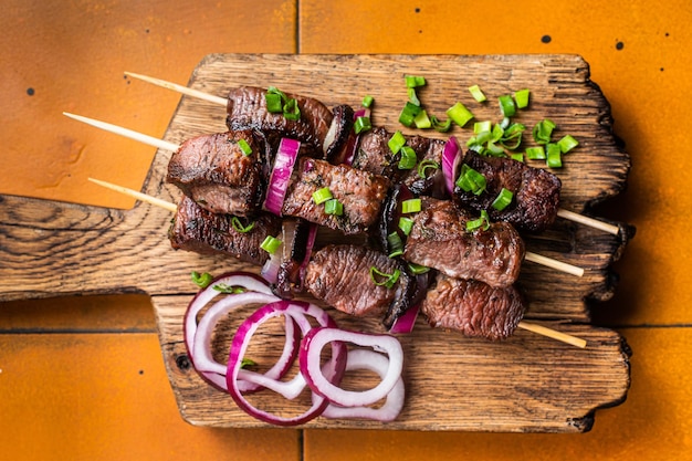 Shish kebab con carne di manzo e carne di agnello cipolla ed erbe su Spiedini Sfondo arancione Vista dall'alto