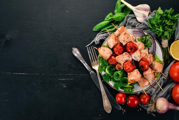 Shish kebab di pollo con pomodorini e verdure. Su uno sfondo di legno. Vista dall'alto. Copia spazio.