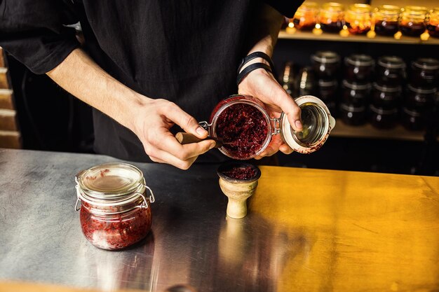 Shisha narghilè preparando dal barman Il barista posa il tabacco per fumare