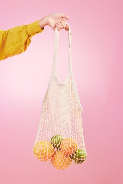 Shopping a mano e borsa con frutta in studio su sfondo rosa per la salute della dieta e affare in materiale di riciclo Sconto di generi alimentari frutta o verdura dal negozio per la sostenibilità alimentare e lo stile di vita