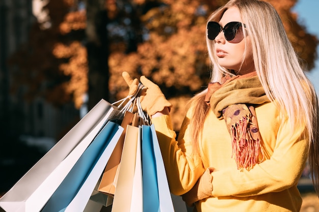 Shopping autunno Elegante signora in piedi con i pacchetti, godendo la giornata di sole autunnale