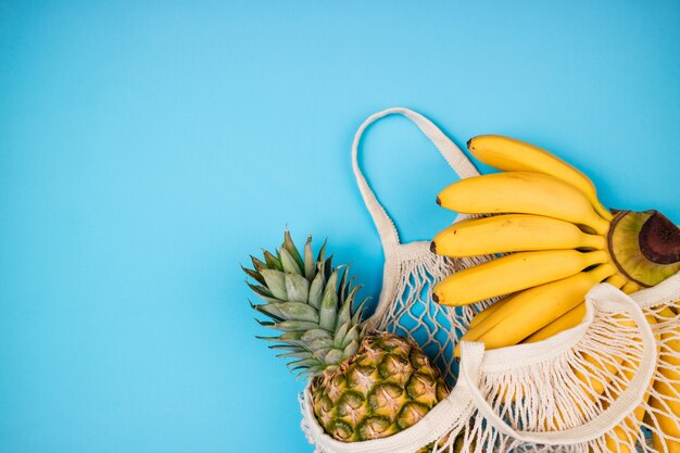 Shopping bag eco friendly con banana biologica e frutta ananas su sfondo blu