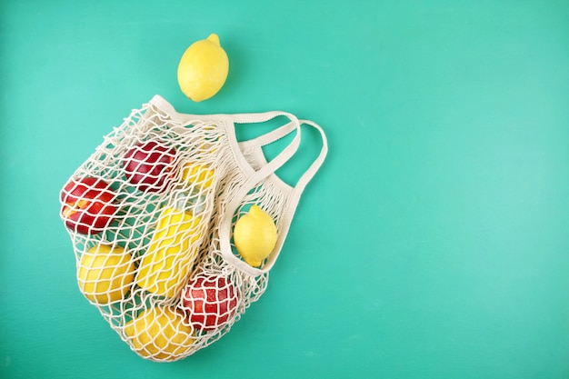 Shopping bag riutilizzabile in rete con limoni, frutta e bottiglia di vetro