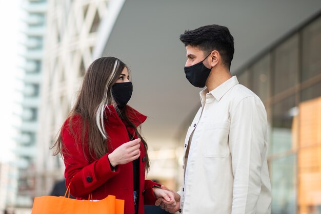 Shopping di Covid e coronavirus, giovane coppia che cammina in una città mentre trasporta borse della spesa