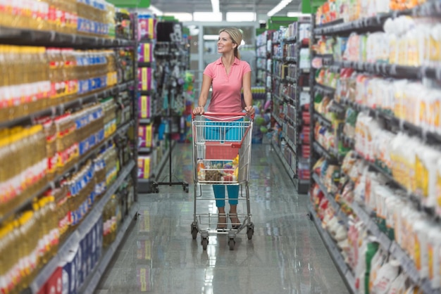 Shopping Donna guardando gli scaffali del supermercato Ritratto di una giovane ragazza in un negozio di mercato con un carrello