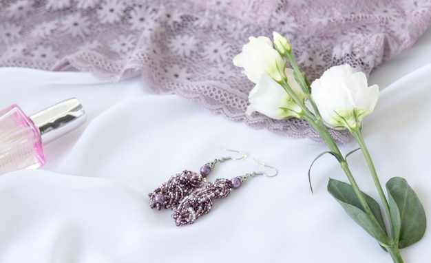 Shopping e concetto di moda. Reggiseno di pizzo lavanda elegante donna, fiori, gioielli, cosmetici su sfondo bianco. Disposizione piana della biancheria alla moda.