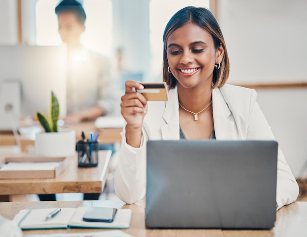 Shopping online con carta di credito e donna d'affari che legge le informazioni per il pagamento del prodotto sul web Lavoratore indiano felice della vendita su internet con il computer alla scrivania in un ufficio al lavoro