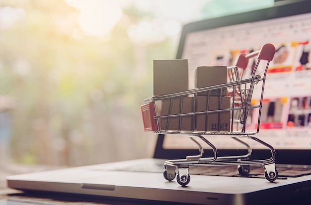 Shopping online concept. Parcel or Paper cartons with a shopping cart logo in a trolley on laptop keyboard. Shopping service on The online web. offers home delivery.