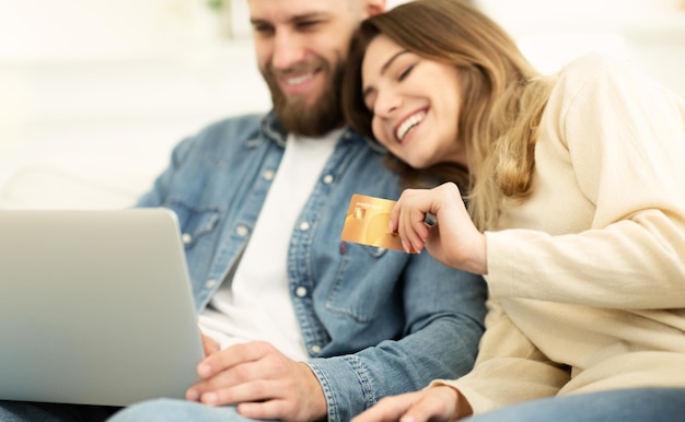 Shopping online coppia felice utilizzando laptop e carta di credito