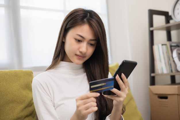 Shopping online Giovane adolescente asiatica inserire il numero di serie della carta di credito sullo smartphone per il pagamento dello shopping Acquista la consegna online dell'oggetto a casa Donna sorridente felice