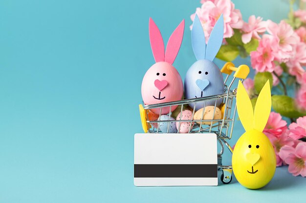 Shopping online Ordinazione Pasqua Carrello con uova carta di credito su sfondo blu Negozio online Concetto di vendita