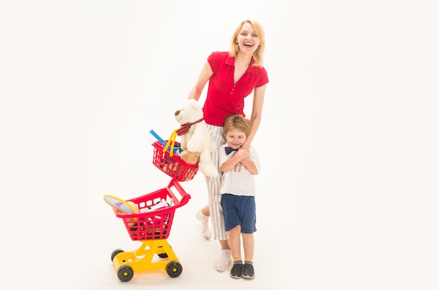 Shopping, sconto, concetto di vendita. Madre con figlio a fare shopping. Ragazzino felice con la madre in negozio. Il bambino gioca in negozio. Ragazzo allo shopping. Ragazzino con carrello della spesa in plastica.