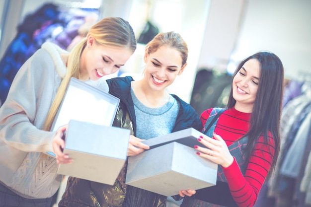 Shopping Tre belle ragazze felici in una boutique che scelgono le scarpe