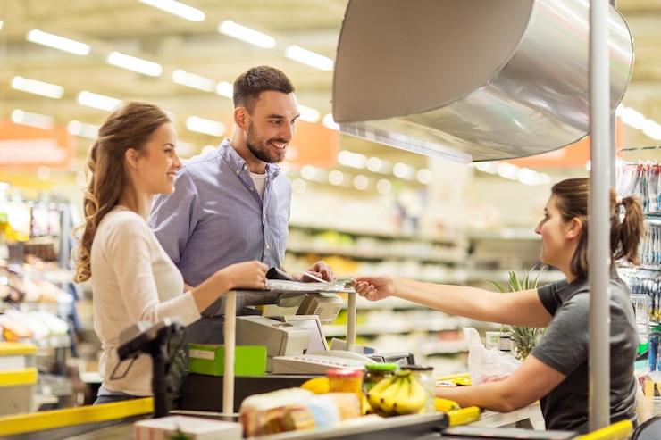 Foto shopping, vendita, consumismo e concetto di persone - coppia felice che compra cibo al negozio di alimentari o alla cassa del supermercato