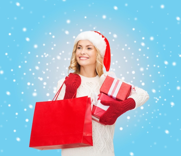 shopping, vendita, regali, natale, concetto di natale - donna sorridente con cappello da Babbo Natale con borse della spesa e scatole regalo