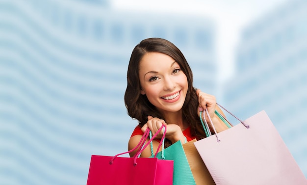 shopping, vendita, regali, natale, concetto di natale - donna sorridente in abito rosso con borse della spesa