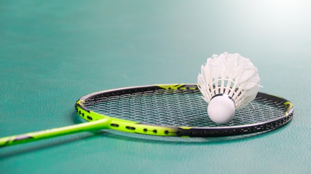 Shuttlecocks bianchi di badminton e racchette di badmington sul pavimento verde campo da badminton coperto morbido e