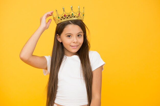 Si adatta perfettamente. la bambina egoista indossa una corona d'oro. piccola principessa. sentirsi campione. infanzia felice. buon concetto di motivazione. lei è un grande capo. orgoglioso della sua ricompensa. lusso e successo.