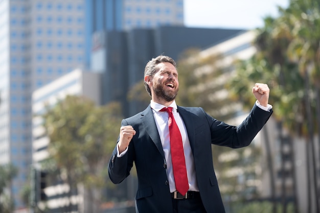 Sì. entusiasmo per gli affari. uomo che esprime positività. ceo professionale barbuto che celebra il successo. l'uomo d'affari maturo sente la felicità. successo aziendale. capo di successo in tuta. imprenditore entusiasta.