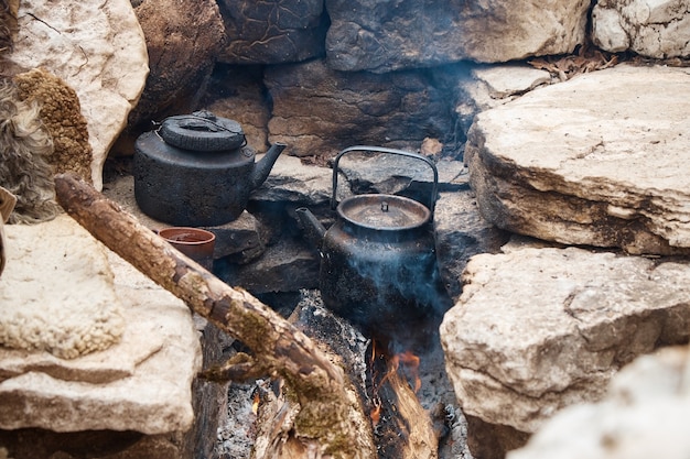 Si scaldano i piatti sul fuoco, si fa bollire l'acqua in un bollitore, una cucina da campo