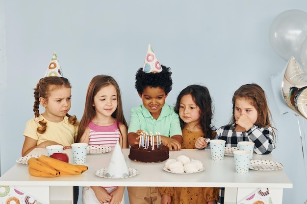 Si siede vicino al tavolo I bambini che festeggiano la festa di compleanno in casa si divertono insieme