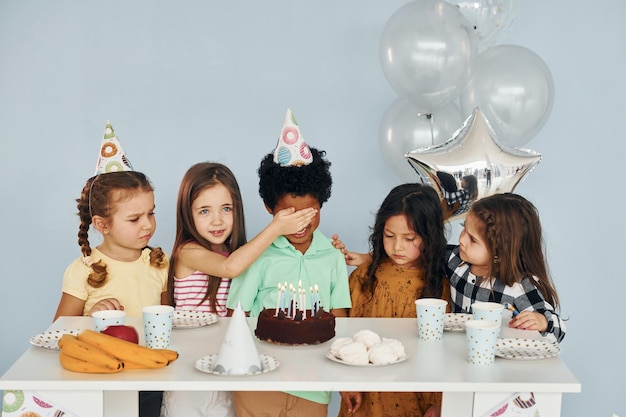 Si siede vicino al tavolo I bambini che festeggiano la festa di compleanno in casa si divertono insieme