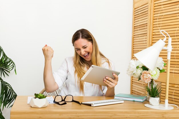 Sì. Stazione di lavoro emozionante felice della donna a casa che trionfa con le mani sollevate