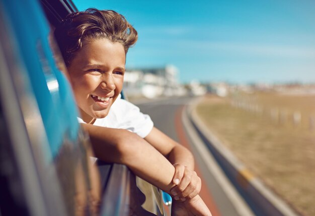 Siamo già arrivati Scatto di un ragazzo felice che si sporge dal finestrino dell'auto durante una gita in spiaggia