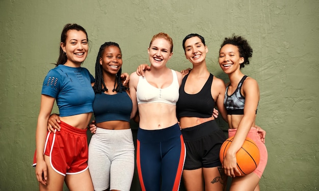 Siamo la definizione dello spirito di squadra Inquadratura ritagliata di un gruppo eterogeneo di sportive in piedi insieme dopo una partita di basket durante il giorno