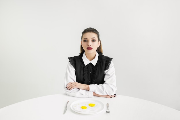 Siamo quello che mangiamo. La donna mangia le uova fritte fatte di plastica, concetto di eco