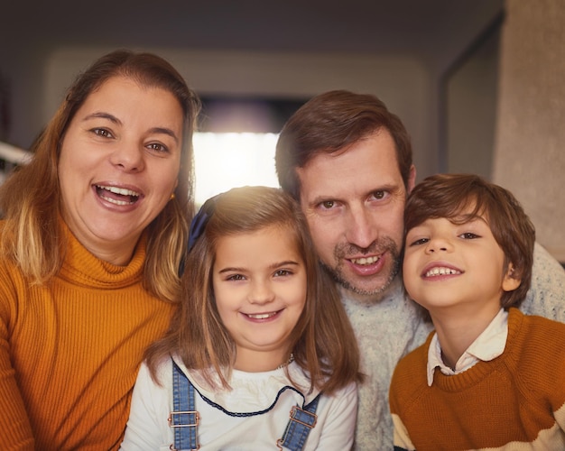 Siamo una famiglia felice Ritratto ritagliato di una giovane famiglia affettuosa di quattro persone seduta sul divano di casa