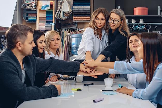 Siamo una squadra. Gruppo prospettico di impiegati professionisti, in segno di motivazione e sostegno, che mettono le mani uno sopra l'altro in un ambiente creativo. Concetto di carico di squadra