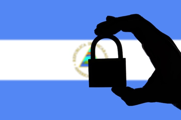 Sicurezza del Nicaragua Silhouette di una mano che tiene un lucchetto sopra la bandiera nazionale