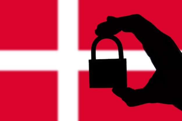 Sicurezza della Danimarca Silhouette della mano che tiene un lucchetto sopra la bandiera nazionale
