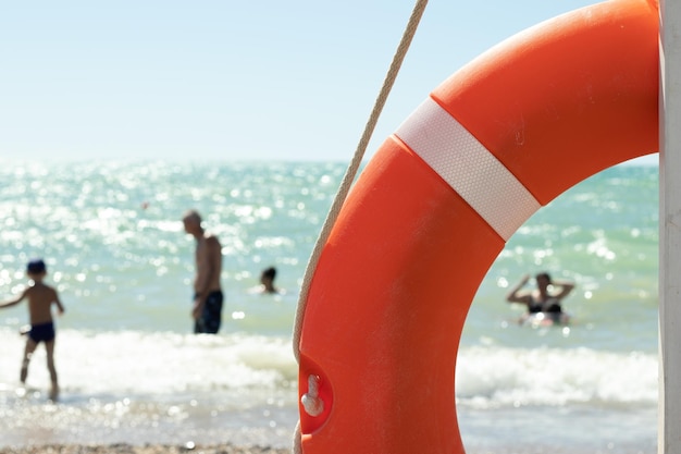 Sicurezza nella località balneare Nuoto sicuro Salvagente arancione e spiaggia con sfondo di persone