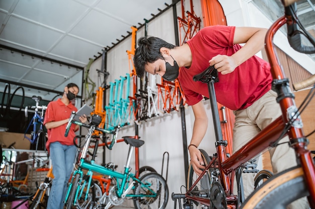 Sicurezza sul lavoro un commesso e una commessa in maschera preparano e controllano le parti della bicicletta