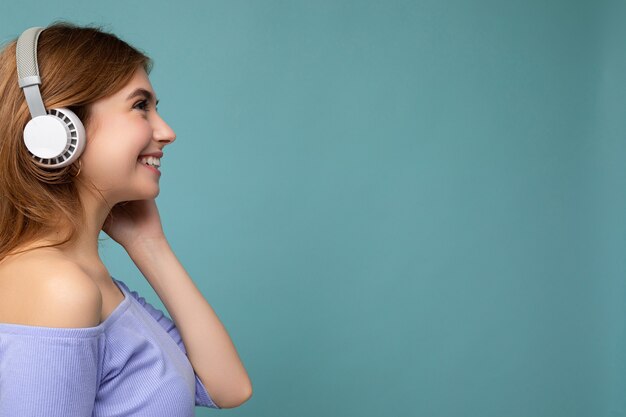 Sideprofile foto ritratto di bella giovane donna bionda sorridente positiva che indossa un top corto blu