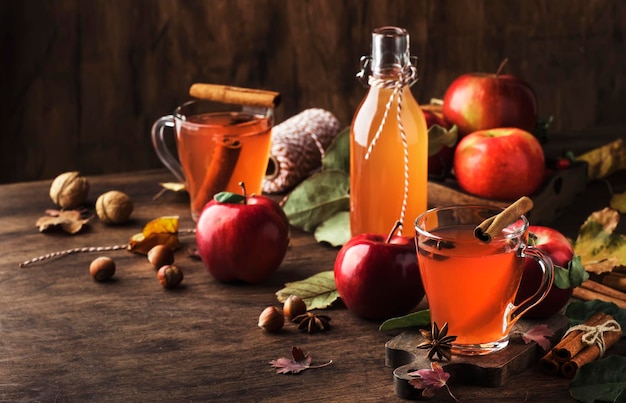 Sidro di mele caldo con bastoncini di cannella chiodi di garofano e anice su sfondo di legno Bevande e cocktail tradizionali autunnali e invernali