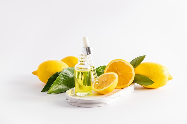 Siero di latte cosmetico di olio di limone con vitamina C in una bottiglia aperta con una pipetta riempita di cosmetici limoni maturi sfondo bianco