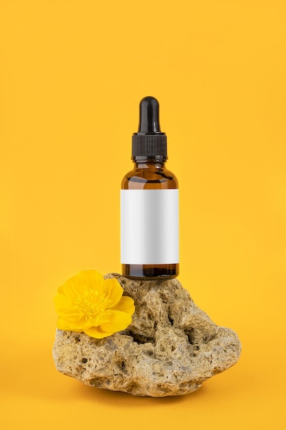 Siero o olio essenziale in bottiglia di vetro marrone con pipetta su pietra e fiori su sfondo arancione Natural Organic Spa Concetto cosmetico Vista frontale